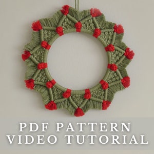 Könnte beinhalten: Ein grüner und roter Makramee-Kranz mit einem Sternmuster. Der Kranz ist aus Garn gefertigt und hat rote Quasten an den Rändern.