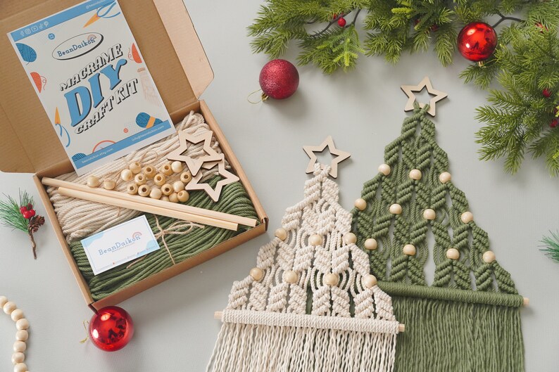 May include: A DIY macrame Christmas tree craft kit with two wooden stars, green and white yarn, wooden beads, and two wooden dowels. The kit comes in a brown box with a label that says "Macrame DIY Craft Kit".
