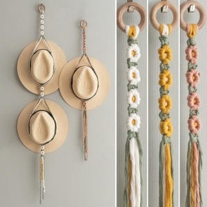 May include: Three straw hats suspended on a wall by macrame hangers. The hangers have wooden rings, beads, and tassels. Close-up images show macrame flower designs in white, yellow, and pink. The hats are a natural colour.