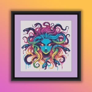 Puede incluir: Una obra de arte en punto de cruz enmarcada que presenta una representación vibrante de Medusa. La obra de arte muestra la cara de Medusa con piel azul, ojos ardientes y una cabeza de serpientes en tonos de azul, morado, amarillo y verde. La pieza está enmarcada en un marco negro con un passe-partout lavanda.