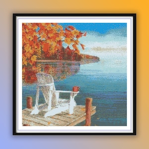 Puede incluir: Una silla Adirondack blanca se encuentra en un muelle de madera con vistas a un lago. El agua está tranquila y azul, y el cielo es de un azul claro con algunas nubes. Los árboles de la orilla están en los colores otoñales de rojo, naranja y amarillo.