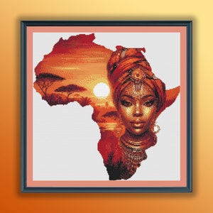 Peut inclure: Une œuvre d'art de point de croix encadrée représentant le visage d'une femme avec un turban rouge, sur fond de coucher de soleil sur le continent africain.