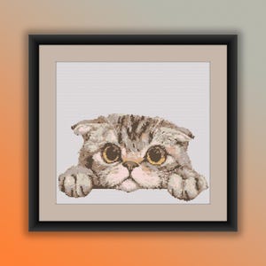 May include: A cross-stitch pattern of a gray and brown tabby cat with large, round eyes peeking over a white surface. The cat has a folded ear and is looking directly at the viewer.