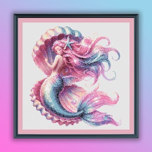 May include: A cross-stitch pattern featuring a mermaid with pink hair and a blue tail, resting inside a large pink seashell.