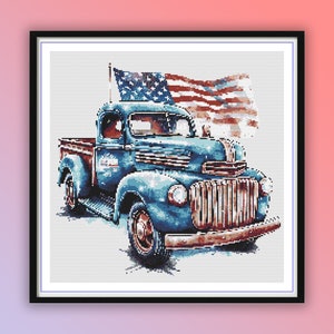 Op de afbeelding: Een vintage blauwe pick-up truck met een vervaagde Amerikaanse vlag gedrapeerd over de cabine. De truck heeft een houten laadbak en een chromen bumper.