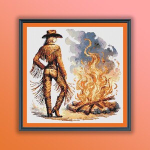 May include: A woman wearing a brown cowboy hat and a brown leather jacket with fringe stands in front of a campfire. The fire is burning brightly and the smoke is rising up into the air.