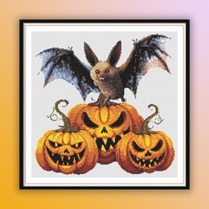 May include: A brown bat with black wings perched on top of three orange pumpkins with scary faces. The pumpkins are on a white background.