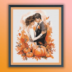 Puede incluir: Una pintura de una pareja abrazándose en un entorno otoñal. La pareja está rodeada de hojas naranjas y rojas y calabazas. La pintura está enmarcada en un marco negro.