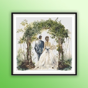 May include: A bride and groom stand under a leafy archway, walking away from the viewer. The bride is wearing a white gown with a blue sash and the groom is wearing a blue suit. The background is a light grey with green foliage.
