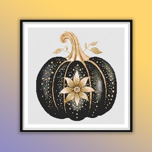 Puede incluir: Una calabaza negra con purpurina dorada y una flor dorada en el centro. La calabaza está enmarcada en un marco negro.