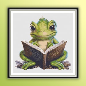 May include: A green frog with large eyes sits on a book, reading. The frog is wearing a small crown and has a friendly expression.