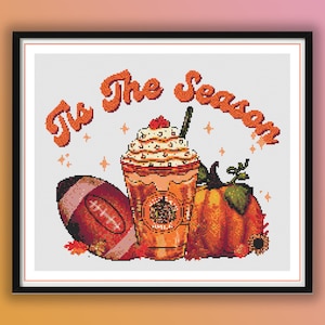 May include: A cross-stitch pattern featuring a fall-themed design with the text "It's the Season". The design includes a pumpkin, a football, and a coffee drink with whipped cream.