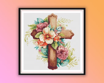 May include: A wooden cross with a floral arrangement of pink, white, and red flowers. The flowers are arranged around the cross and have green leaves.