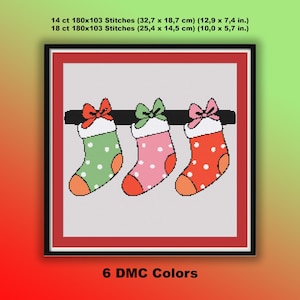 May include: Cross-stitch pattern featuring three Christmas stockings in green, pink, and red, each with white polka dots and a matching bow. The text at the bottom reads "6 DMC Colors". The pattern size is 12.9 x 7.4 inches or 10.0 x 5.7 inches.