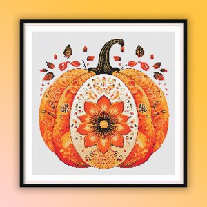 Peut inclure: Un motif de point de croix représentant une citrouille orange avec des motifs floraux complexes et des feuilles d'automne. La citrouille est entourée d'un fond blanc.