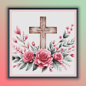 Puede incluir: Una cruz de madera con un acabado rústico está rodeada de rosas rosas y hojas verdes. La cruz está centrada en la imagen y las flores están dispuestas a su alrededor.