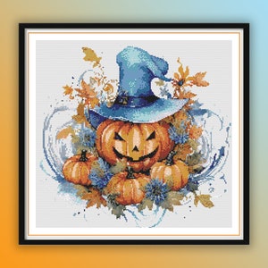 May include: A blue witch's hat sits atop a carved orange pumpkin with a toothy grin. The pumpkin is surrounded by smaller pumpkins and fall foliage, including blue flowers and brown leaves.