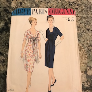 May include: Vintage Vogue Paris Original sewing pattern 1449. The pattern features illustrations of two elegant dresses. The top of the pattern reads "Vogue Paris Original" in blue and red text. The pattern is designed by Griffe.