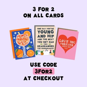 May include: Three greeting cards with colorful illustrations and text. The cards feature a birthday card with a glass of orange juice, a card with the text "One day you're young and hip and the next you get mad they rearranged the supermarket", and a card with a heart and the text "Love you forever and a day". The text "3 for 2 on all cards" is at the top of the image. The text "Use code 3for2 at checkout" is at the bottom of the image.