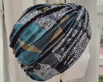 May include: A black, teal, and gold patterned turban with a gold and black dangle earring.