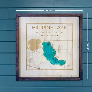 May include: Wooden framed wall art featuring a map of Big Pine Lake, Minnesota. The lake is highlighted in teal, with surrounding land details. The frame and artwork measure 18.25 inches square. The text "BIG PINE LAKE MINNESOTA" is displayed at the top.