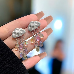 Puede incluir: Pendientes de nube plateados con abalorios de gota de lluvia de arcoíris iridiscente.