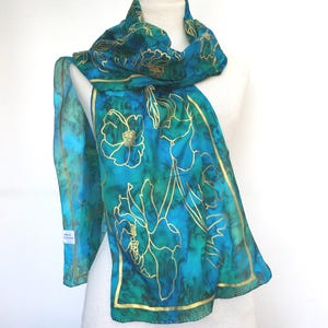 Pure silk scarf with a gold flower design in peacock blue and emerald green. 180cm long (72") in a light weight silk with hand rolled edges.