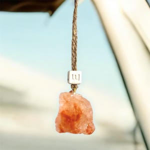 May include: A pink Himalayan salt rock hanging from a brown string with a white tag that says "111".