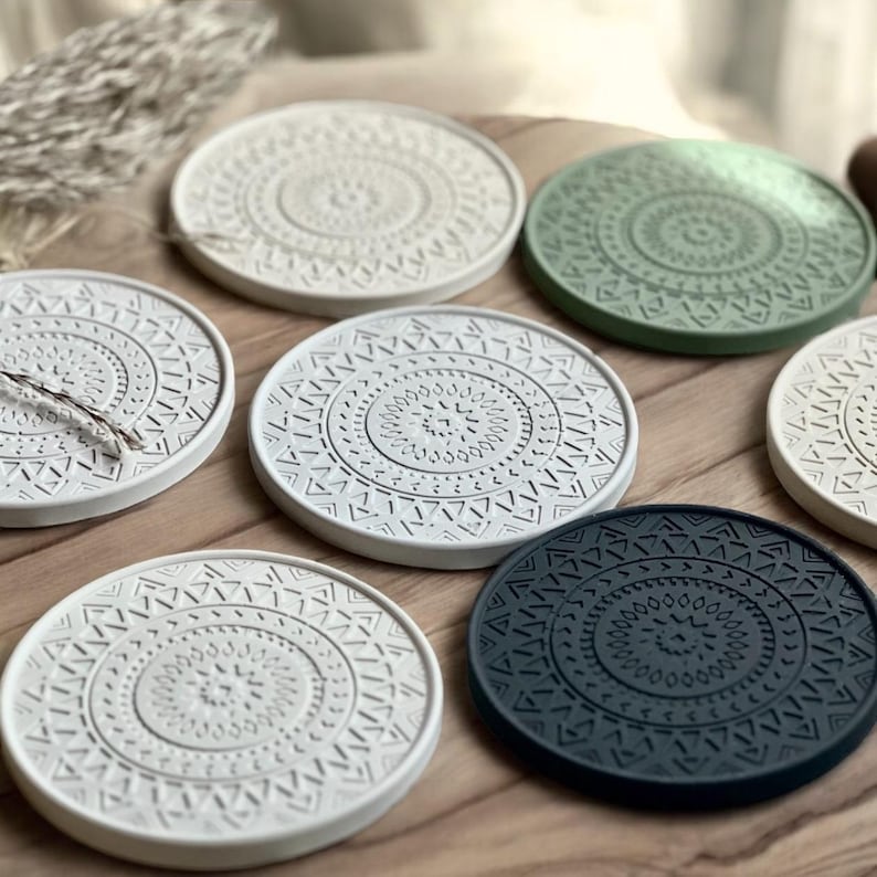 Puede incluir: Seis posavasos redondos con un patr&oacute;n geom&eacute;trico en tonos de blanco, verde y negro. Los posavasos est&aacute;n hechos de un material texturizado y tienen un dise&ntilde;o en relieve.