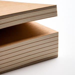 Peut inclure: Gros plan sur deux piles de blocs-notes rectangulaires brun clair. Les blocs-notes ont un aspect rugueux et textur&eacute; et sont empil&eacute;s les uns sur les autres sur un fond blanc. Les bords du papier sont visibles, montrant les feuilles individuelles.