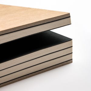 basenotes 2333 sketchbook showing alternating black dividers and natural cream pages with visible hand-stitched binding.