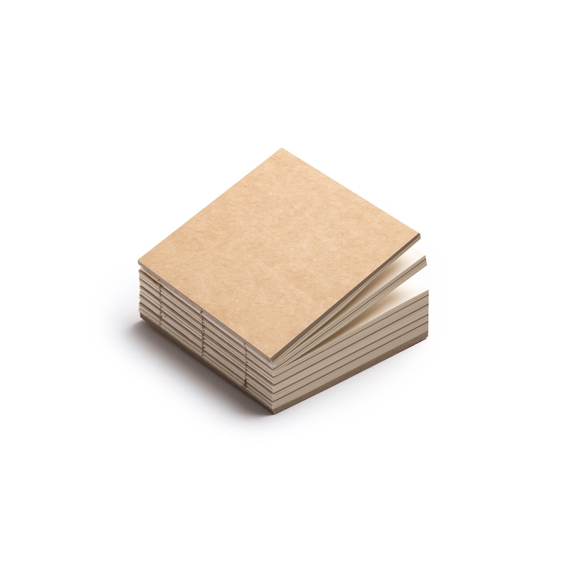 May include: A stack of small square notebooks with kraft paper covers. The pages are off-white, and the binding is visible along the spine. The notebooks are stacked neatly, with a few pages slightly fanned out.