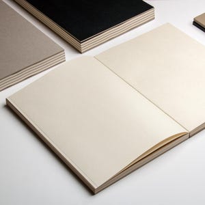 basenotes 2333 sketchbook opened flat showing cream pages and lay-flat binding, surrounded by other colour covers.