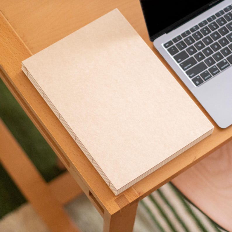 Handmade minimalist sketchbook with cream paper pages on a wooden desk, artisan notebook for sketching and creative work by basenotes