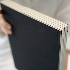 Close-up of the basenotes 2333 sketchbook black cover showing embossed logo and visible hand stitching.