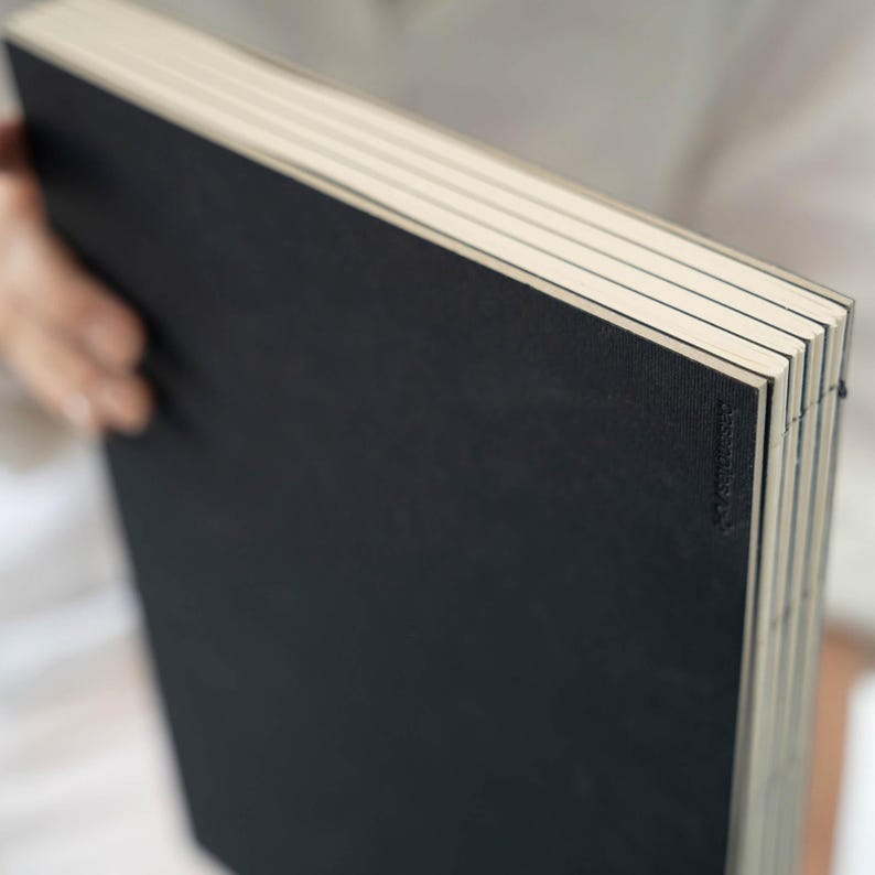 Close-up of the basenotes 2333 sketchbook black cover showing embossed logo and visible hand stitching.