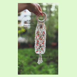 May include: A white macrame bottle holder bag with red and green beads, held by a hand. The bag has a wooden ring handle and a tassel at the bottom. Text on the image reads "PDF Tutorial by Pera Felting" and "Bottle Holder Bag".
