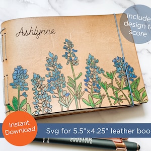 May include: A personalized leather journal with a bluebonnet flower design. The journal is 5.5 inches by 4.25 inches and has a blue string closure. The journal is labeled "Ashlynne" and includes a design to score.