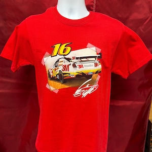 May include: A red t-shirt with a race car graphic. The number 16 is in yellow, and the car has the 3M logo and the word "Innovation". The shirt is displayed on a white mannequin head and torso.