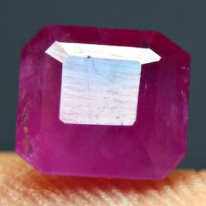 Pode incluir: Uma gema rosa vibrante com um corte quadrado esmeralda. A gema é facetada e tem um alto polimento.