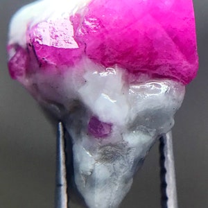 May include: A pink ruby crystal with a white matrix. The ruby is faceted and has a high luster. The crystal is about 1 inch long.