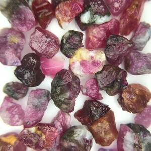 Könnte beinhalten: Eine Sammlung kleiner, rauer, rosa und grüner Edelsteine. Die Edelsteine sind unregelmäßig geformt und haben verschiedene Größen.