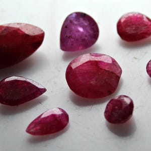 Puede incluir: Surtido de nueve cabujones de piedras preciosas rosas y rojas, incluyendo formas ovaladas, de pera y redondas.