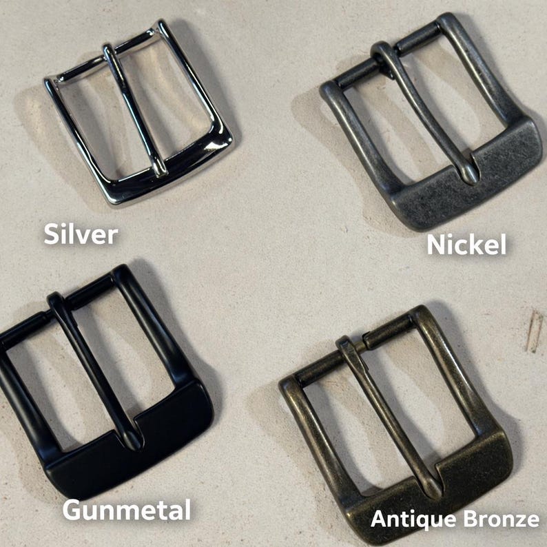 May include: Four square belt buckles in different finishes: a shiny silver, a matte nickel, a smooth black gunmetal, and a textured antique bronze. Each buckle features a central prong and a rectangular frame, labeled with their respective color names.