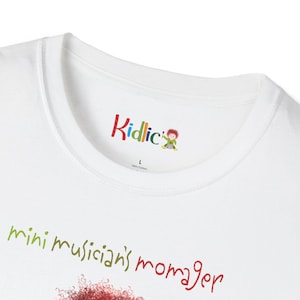 May include: White t-shirt with the text "mini musician's manager" in green and red. The shirt has a colourful "Kidlic" logo at the neckline. The shirt is made of 100% cotton and is a size large.