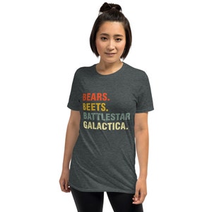 Pu&ograve; includere: Una t-shirt grigio scuro melange con il testo "BEARS. BEETS. BATTLESTAR GALACTICA." stampato in stile retr&ograve; con colori rosso, arancione, giallo e verde.