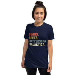 Pu&ograve; includere: Una t-shirt blu navy con una grafica in stile vintage che recita "BEARS. BEETS. BATTLESTAR GALACTICA."