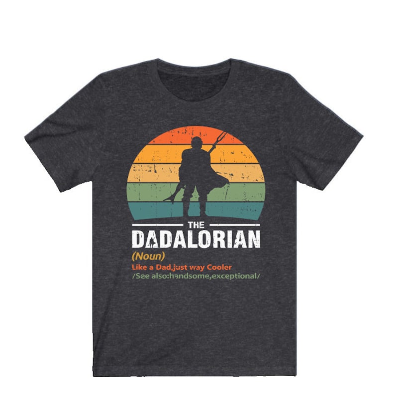 May include: Dark grey t-shirt with a retro sunset design and a silhouette of a figure with a weapon. The text reads "THE DADALORIAN (Noun) Like a Dad, just way Cooler /See also: handsome, exceptional/."