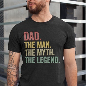 Könnte beinhalten: Ein dunkelgraues T-Shirt mit einer Grafik im Vintage-Stil, auf dem "DAD. THE MAN. THE MYTH. THE LEGEND." steht.