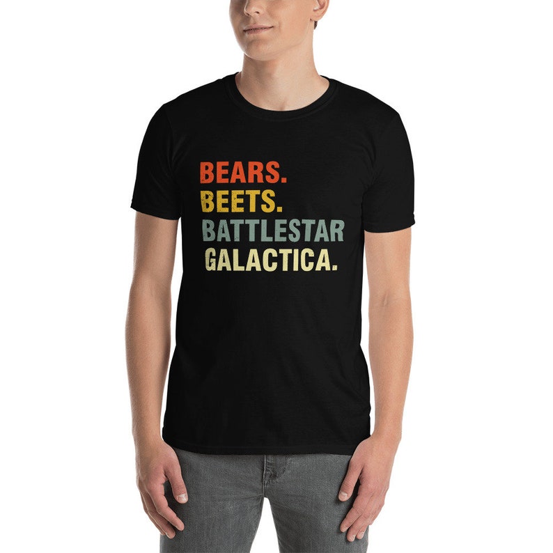 Pu&ograve; includere: Una maglietta nera con una grafica in stile vintage che recita "BEARS. BEETS. BATTLESTAR GALACTICA."